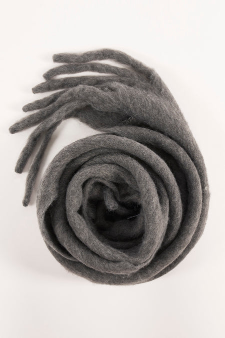Écharpe verte par PIECES®, tricotée en spirale avec des extrémités longues et retombantes, sur fond clair.
