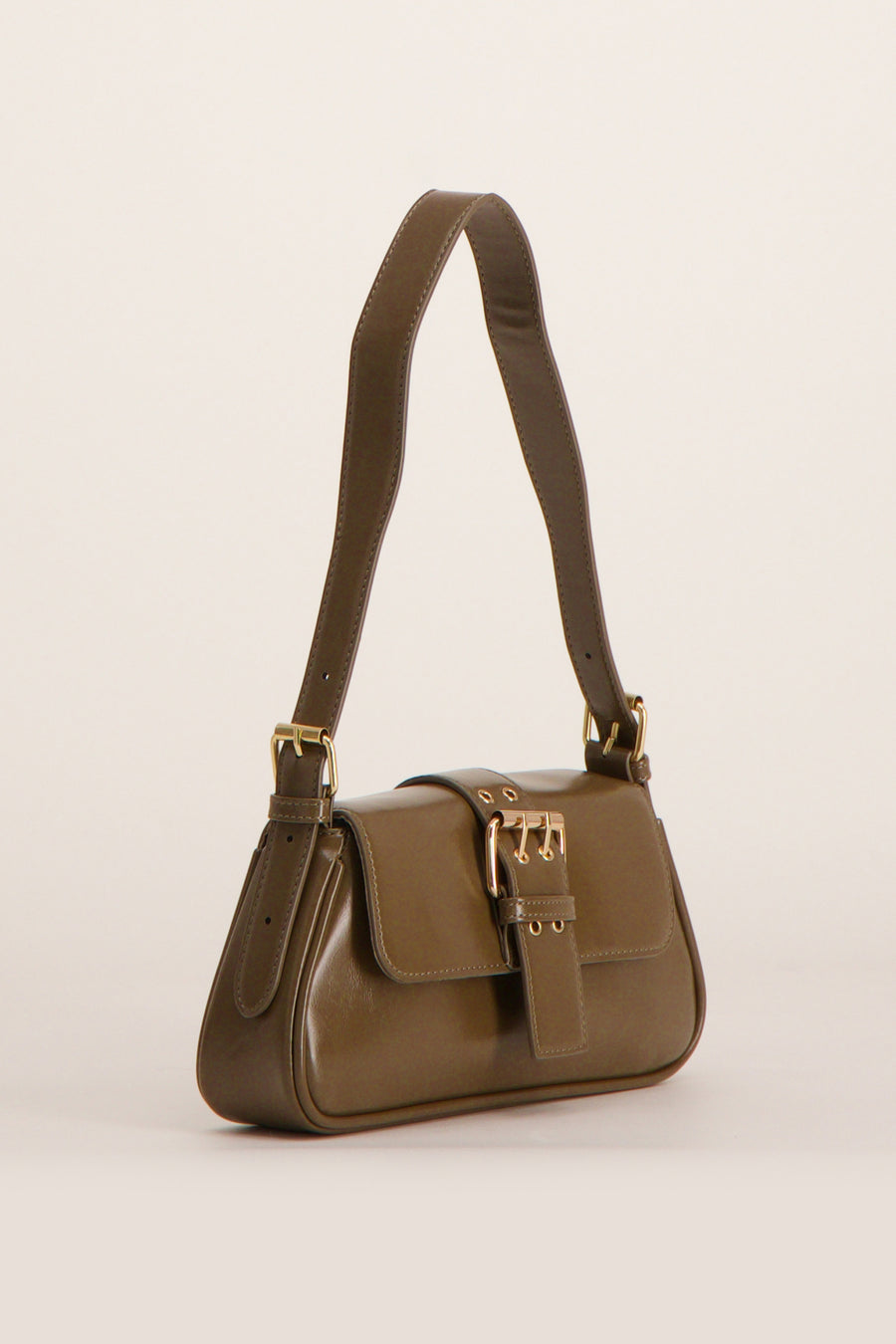 Sac à bandoulière brun de PIECES®, avec une boucle dorée sur le devant, porté par sa bandoulière.