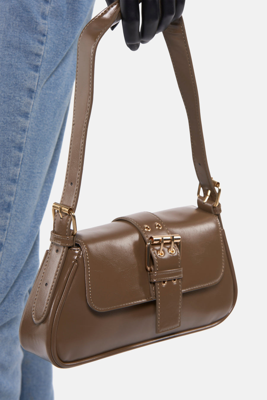 Bruine schoudertas van PIECES® met gouden gesp, gedragen met een blauwe jeans.