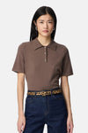 Zwarte leren riem van PIECES®, gedragen met een bruin poloshirt en een blauwe spijkerbroek.