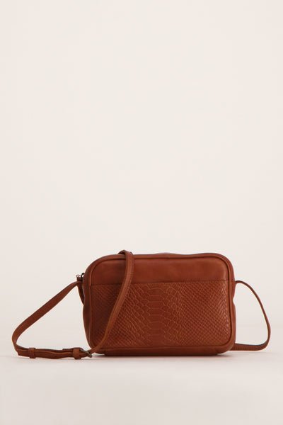 Sac à bandoulière marron en cuir, par PIECES®, avec un motif serpent texturé sur le devant.
