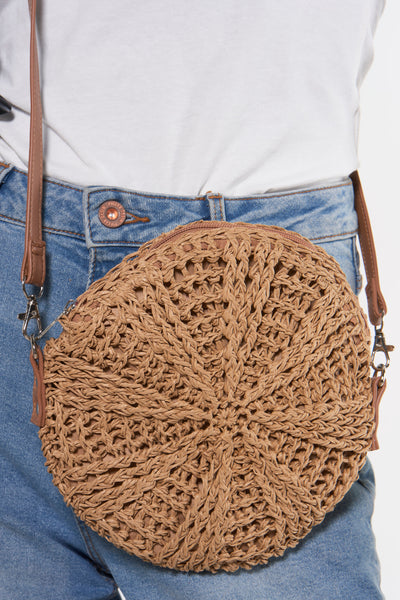 Sac à bandoulière en paille marron de PIECES®, porté avec un jean et un t-shirt blanc.