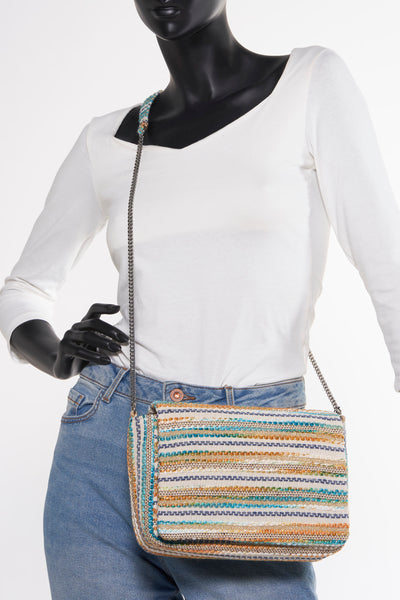 Multikleuren handtas van PIECES®, met zilverkleurige kettingriem, gedragen door een paspop in spijkerbroek en wit T-shirt.