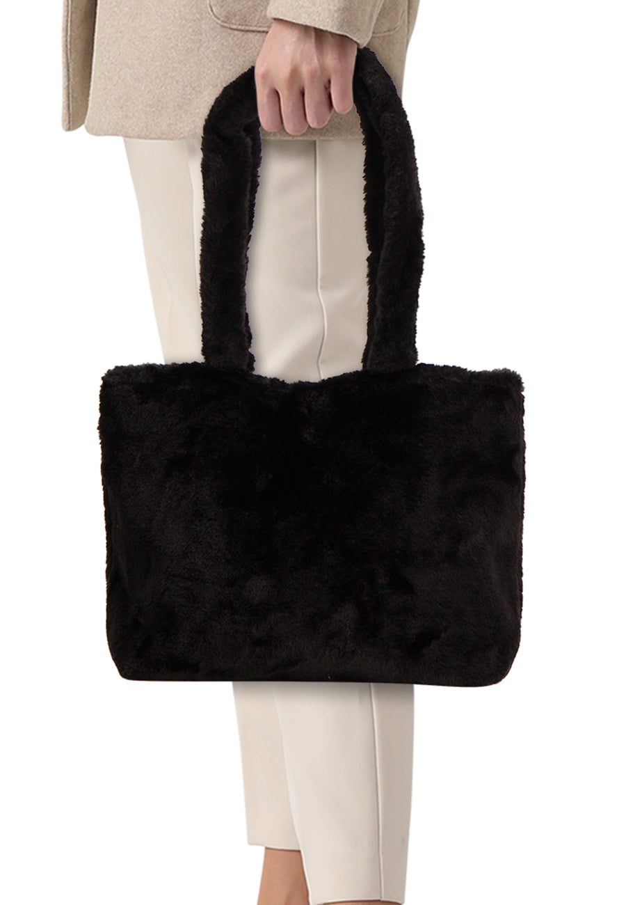 Sac à bandoulière noir en fausse fourrure de PIECES®, porté avec un manteau beige et un pantalon blanc.