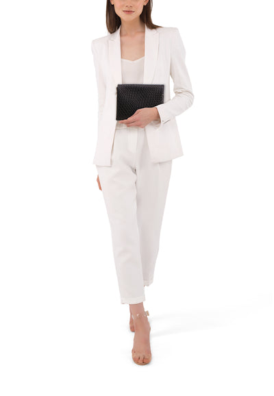 Sac à bandoulière noir de PIECES®, porté avec un tailleur pantalon blanc et des sandales transparentes.
