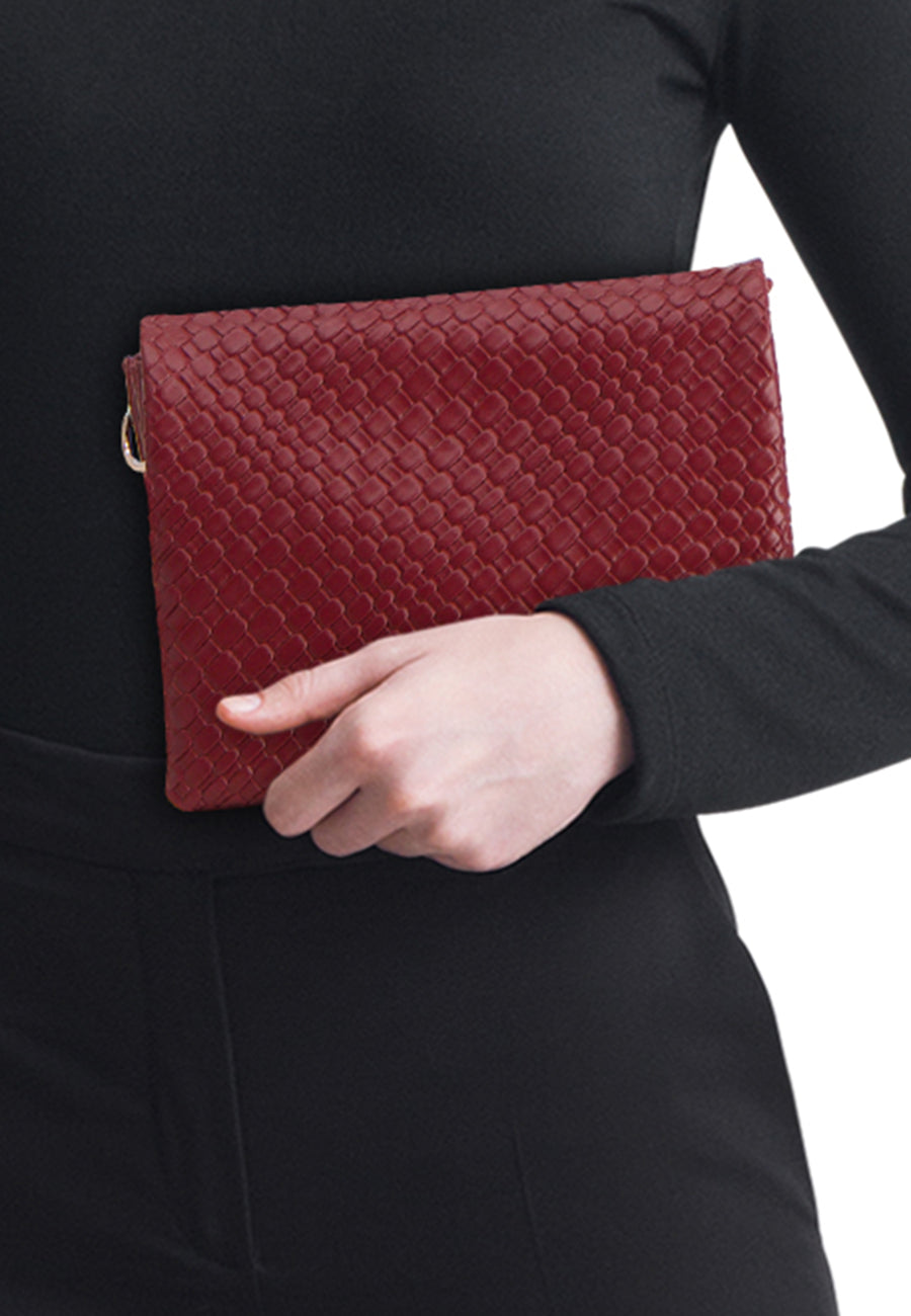Sac à bandoulière bordeaux en cuir tressé de PIECES®, porté à la main, avec vêtement noir.
