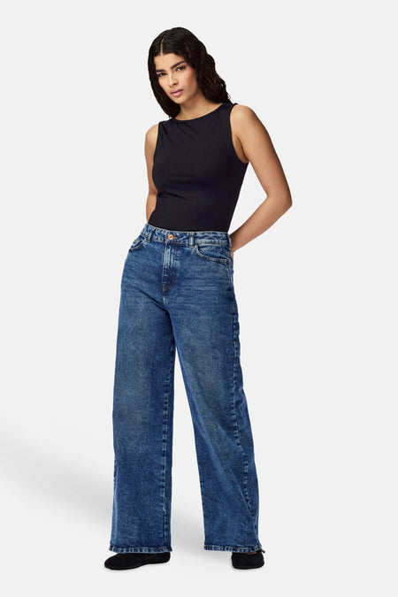 Zwart body van PIECES®, ronde hals, mouwloos, gedragen met een wijde jeans en platte schoenen.