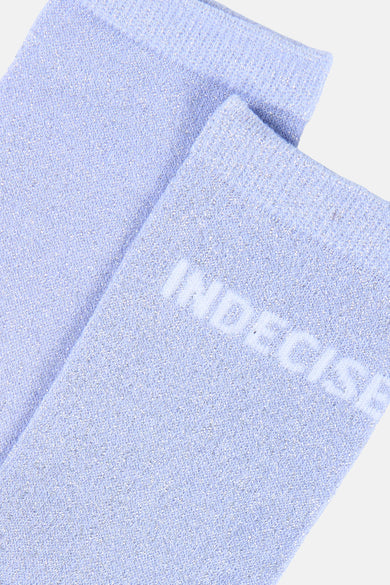 Chaussettes bleu lavande scintillantes de PIECES® avec le mot 'INDECISIVE' brodé et un motif tricoté en zigzag.