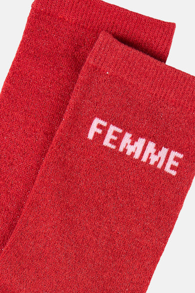 Chaussettes rouges scintillantes de PIECES® avec le mot « FEMME » en lettres blanches.