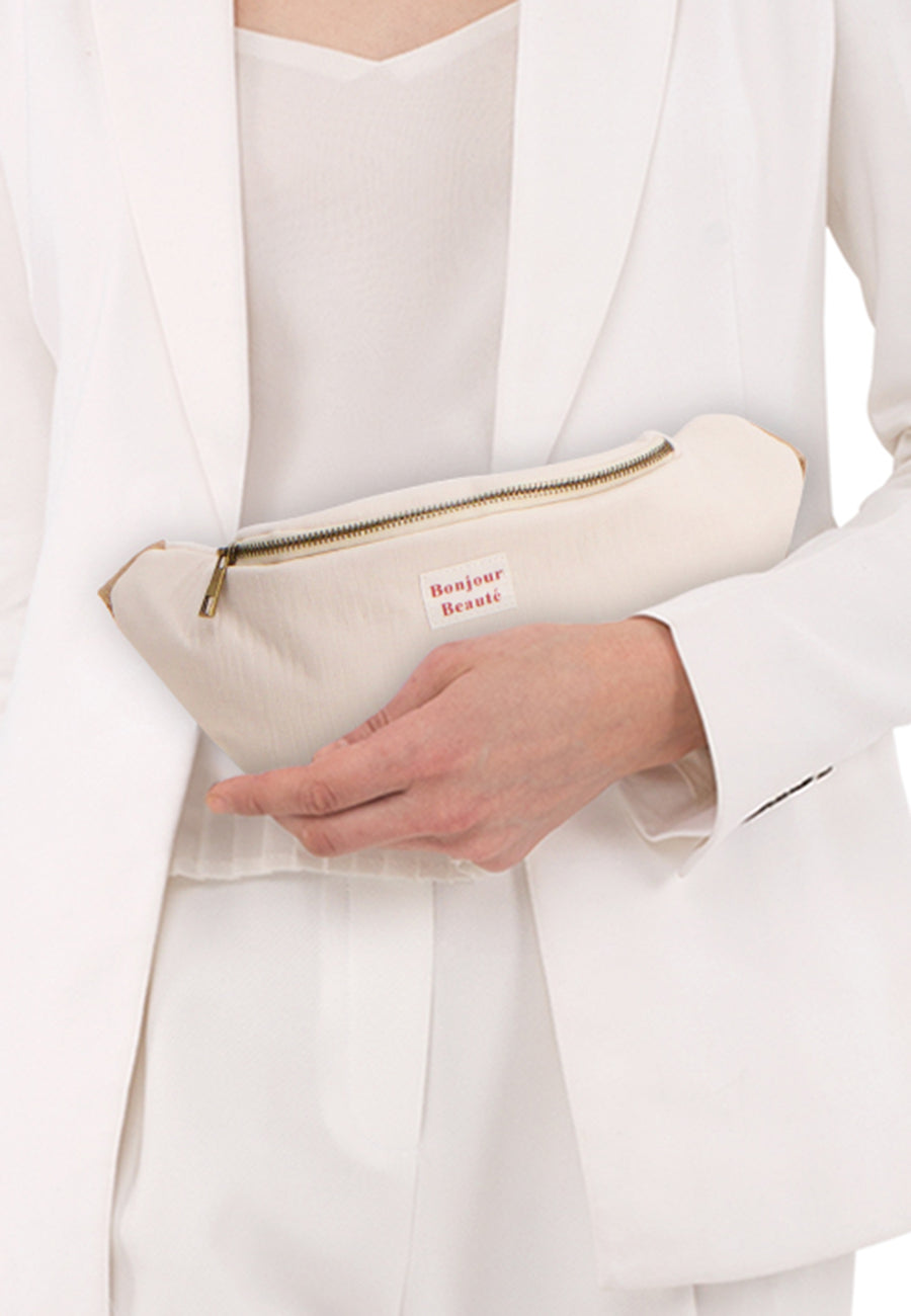 Sac à bandoulière beige de PIECES®, porté avec un tailleur blanc et un top assorti.