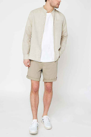 Korte beige short van Levi's, met achterzakken met knopen en gedragen met witte schoenen met strepen.