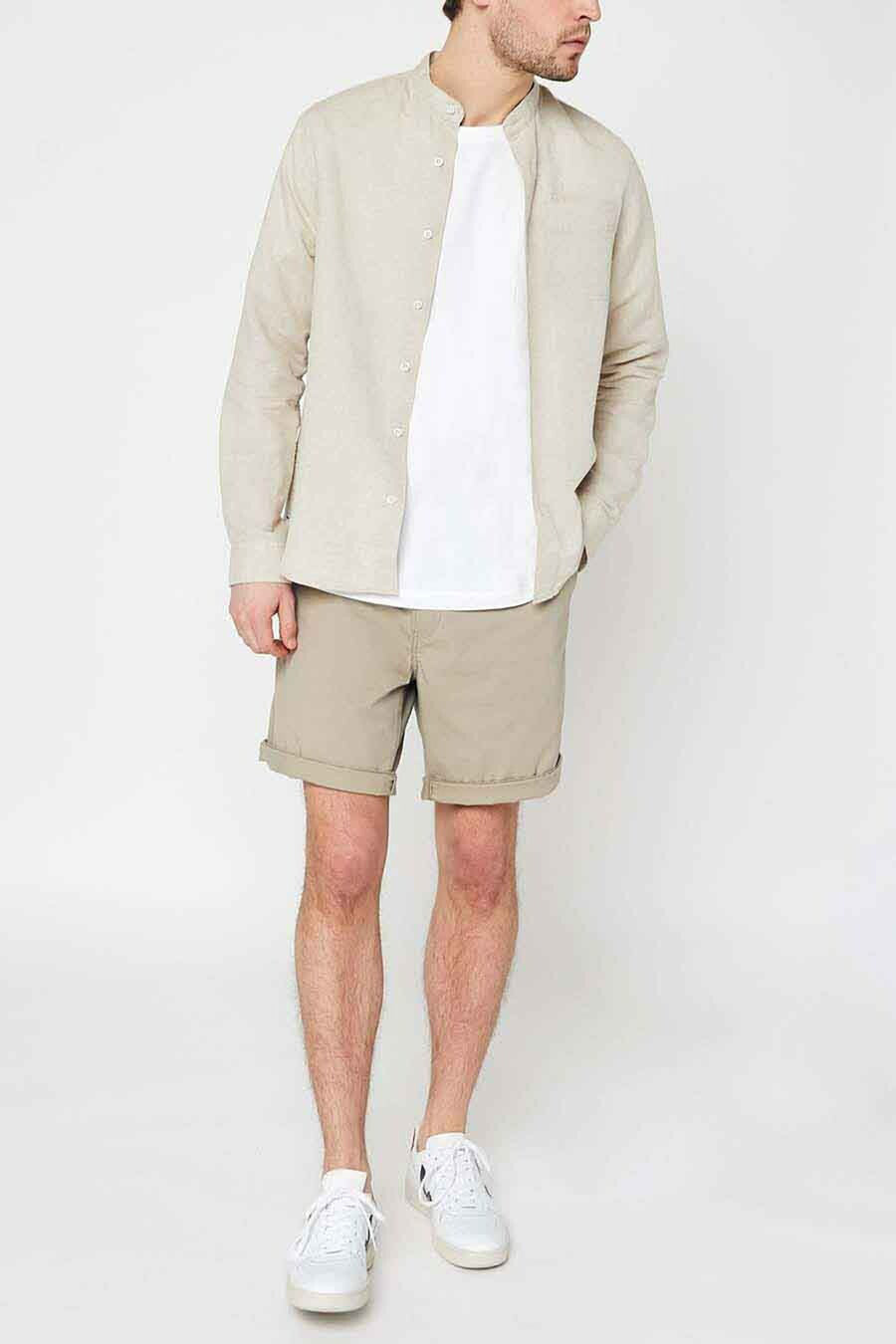 Korte beige short van Levi's, met achterzakken met knopen en gedragen met witte schoenen met strepen.