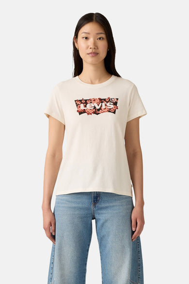 Beige T-shirt met korte mouwen van Levi's, versierd met een bloemenpatroon op het logo, gedragen met een blauwe spijkerbroek.