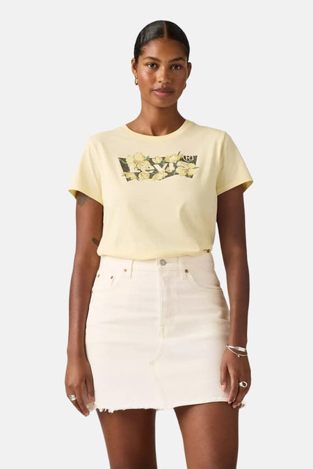 T-shirt à manches courtes jaune de Levi's orné d'un motif floral sur le devant, porté avec une jupe blanche.