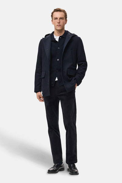 Veste courte bleu foncé de MANGO, portée avec un cardigan et un pantalon en velours côtelé, et des mocassins noirs.

