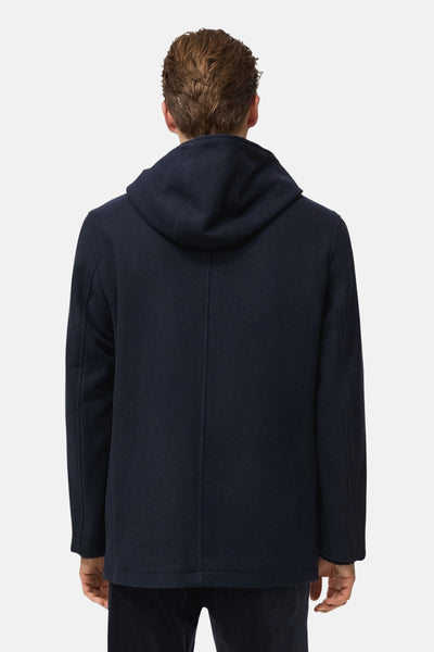Veste courte bleu foncé de MANGO, avec une capuche visible de dos, sur un fond uni.
