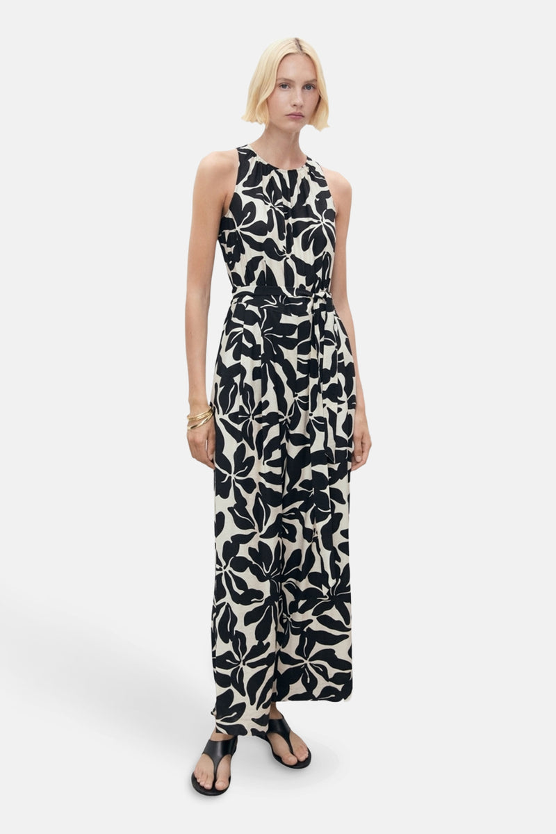 Zwarte jumpsuit met bloemenprint van MANGO, met een strikceintuur in de taille en zwarte sandalen.