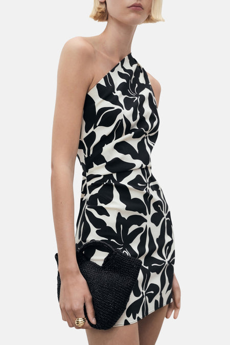 Robe courte imprimée multicolore de MANGO, avec motif floral noir et blanc, portée avec un sac noir texturé.
