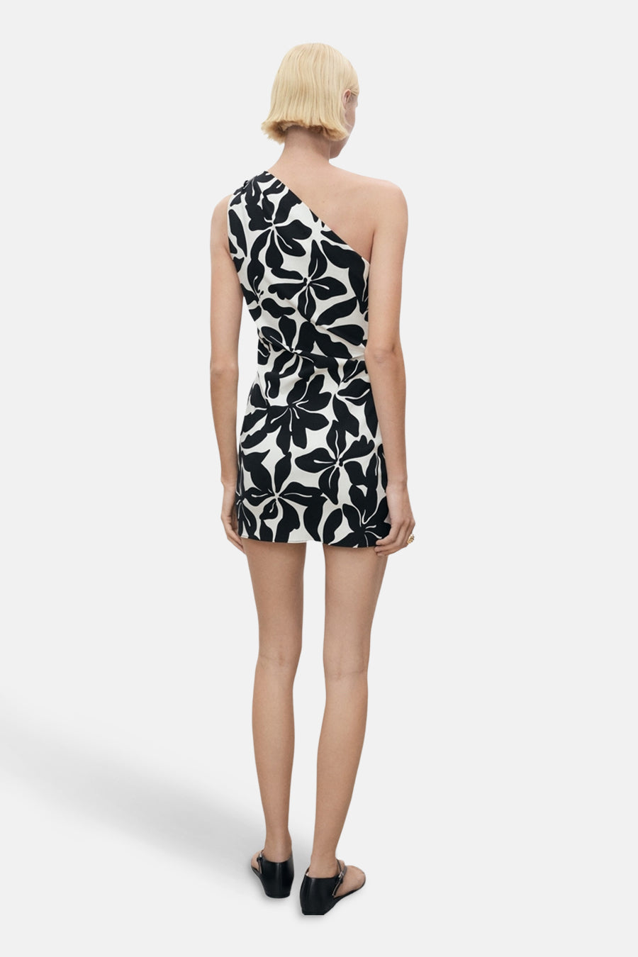 Korte veelkleurige jurk van MANGO, met zwart-wit bloemenpatroon, rug zichtbaar en zwarte schoenen.