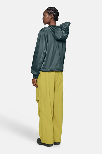 Dark green shiny hooded jacket with elastic cuffs, side view, worn with olive cargo pants and black shoes
