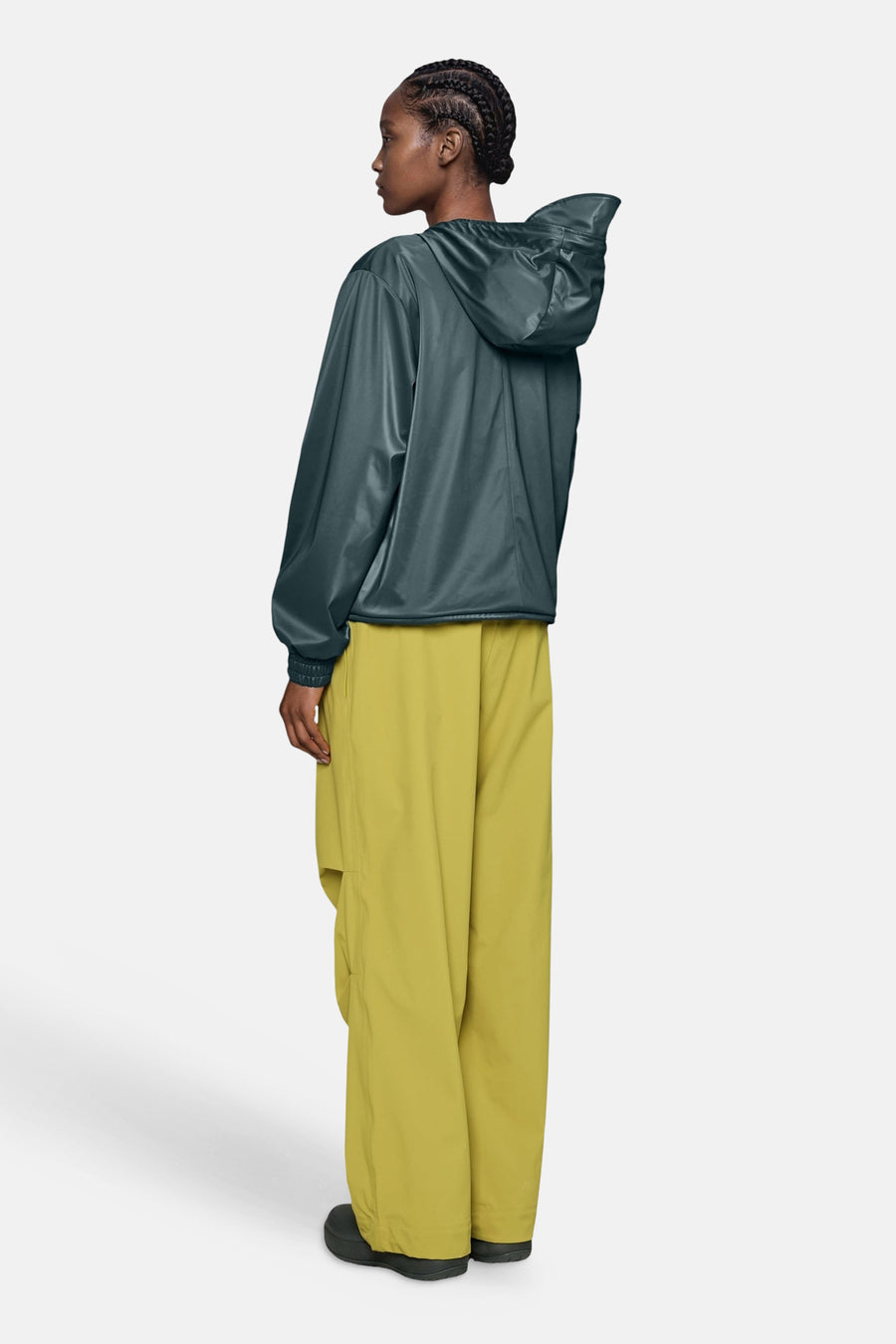Dark green shiny hooded jacket with elastic cuffs, side view, worn with olive cargo pants and black shoes