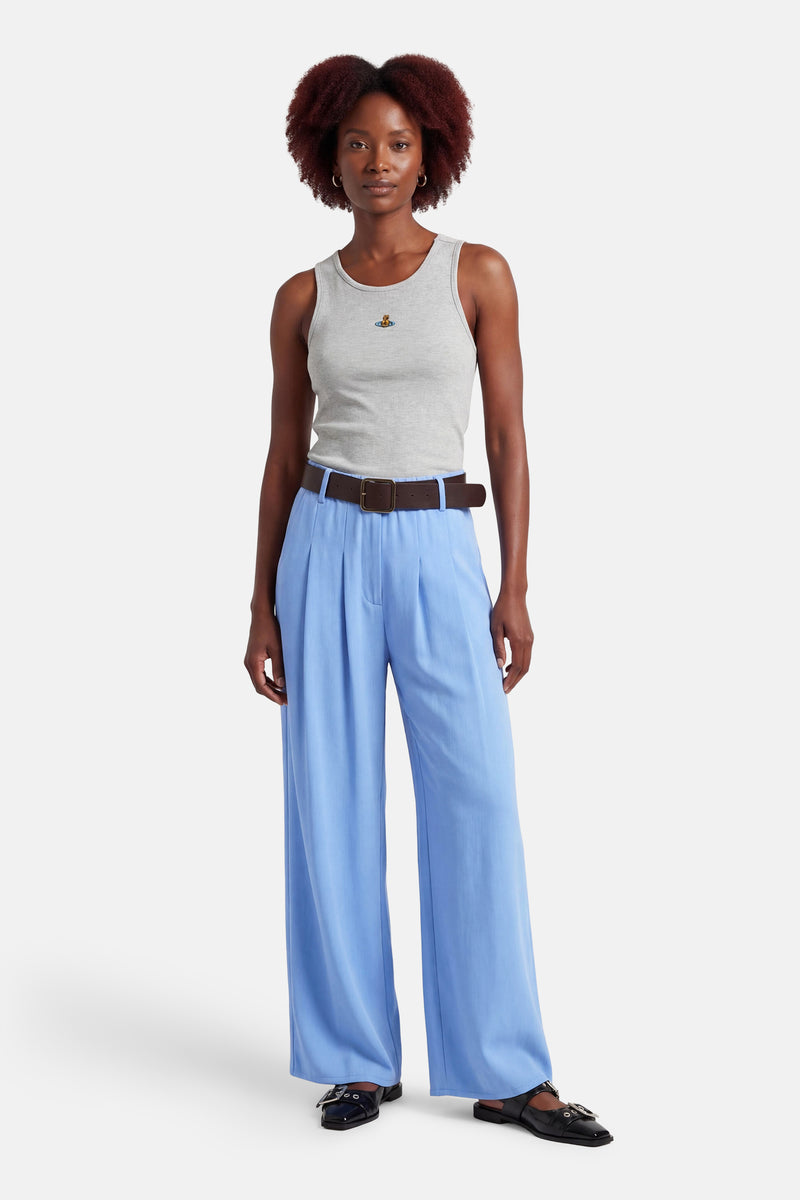 Pantalon de costume bleu Terra di Siena ample à plis, porté avec ceinture marron et chaussures noires.
