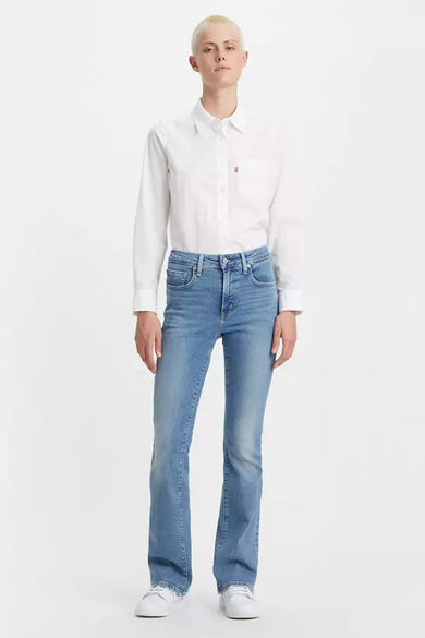 Jean bootcut bleu de Levi's, porté avec une chemise blanche à manches longues et des baskets blanches.