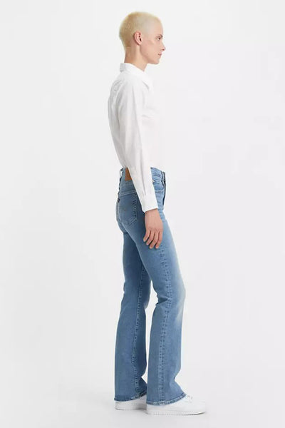 Jean bootcut bleu de Levi's, porté avec une chemise blanche à manches longues et des chaussures blanches.