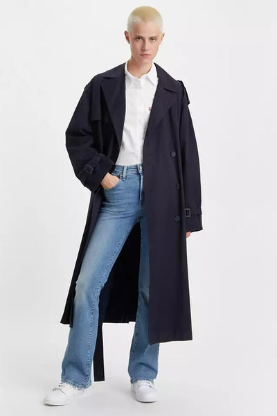 Jean bootcut bleu de Levi's®, porté avec une chemise blanche et un trench coat noir long.