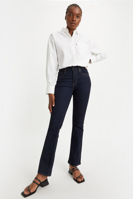 Jean bootcut en denim bleu foncé de Levi's, porté avec une chemise blanche et des sandales noires.
