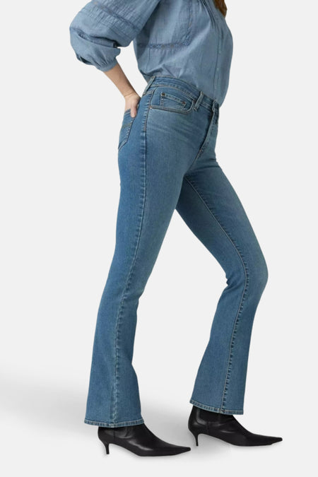 Middelblauwe bootcut jeans van Levi's, gedragen met een spijkerblouse en zwarte naaldhak enkellaarsjes.