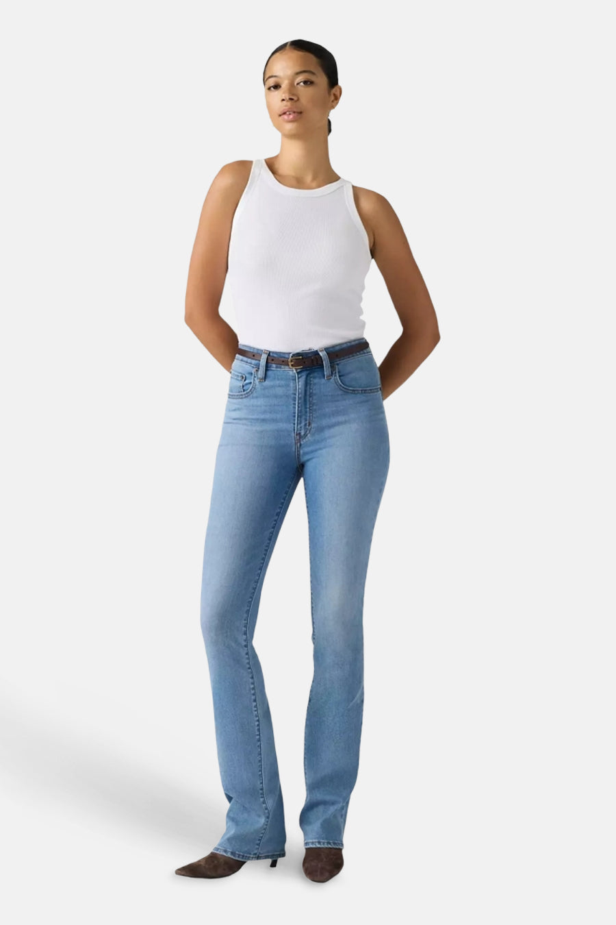 Mid blue bootcut jeans by 725, featuring classic five-pocket design, subtle fading, and straight leg flare, worn with white tank top and brown belt.