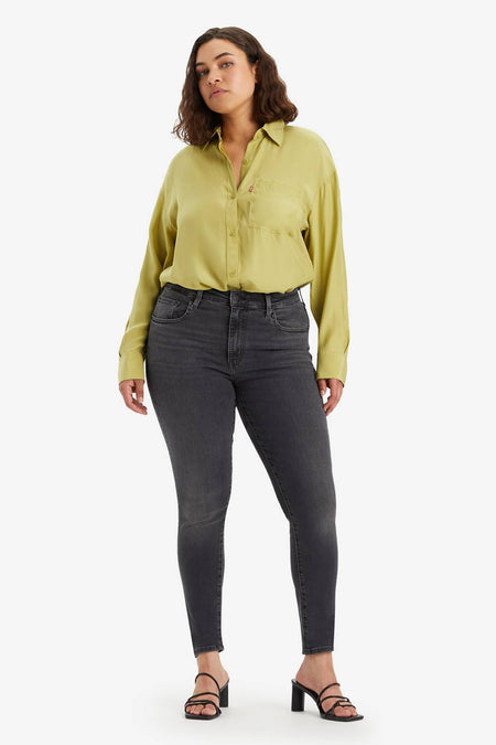 Jean skinny en denim gris foncé de Levi's, porté avec une chemise vert chartreuse et des talons noirs.
