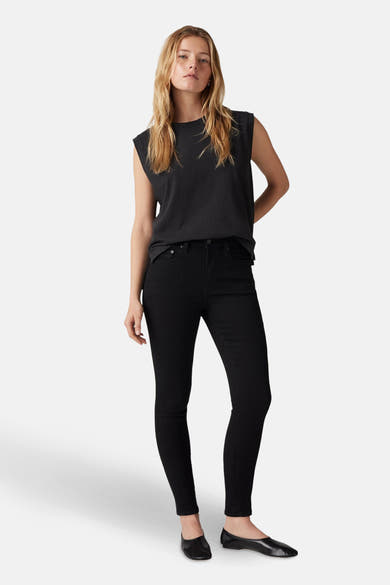 Jean skinny noir de Levi's®, porté avec un t-shirt noir sans manches et des ballerines en cuir noir.