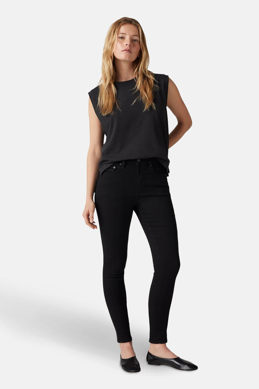 Jean skinny noir de Levi's®, porté avec un t-shirt noir sans manches et des ballerines en cuir noir.