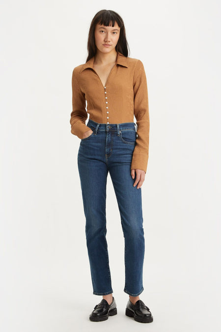 Jean droit bleu de Levi's, porté avec un haut marron boutonné et des chaussures noires.
