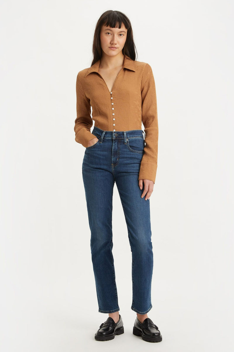 Jean droit bleu de Levi's, porté avec un haut marron boutonné et des chaussures noires.
