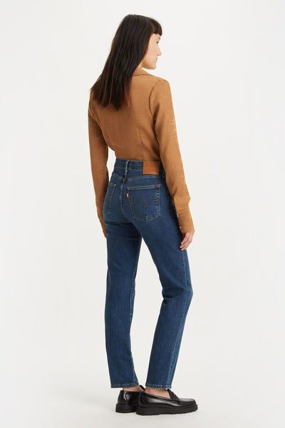 Jean droit bleu de Levi's, avec une coupe classique et une taille haute, porté avec un chemisier marron.
