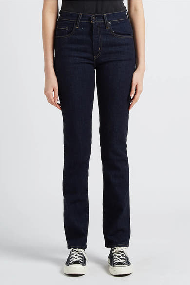 Rechte donkerblauwe spijkerbroek van Levi's, achterzakdetails en Converse schoenen.