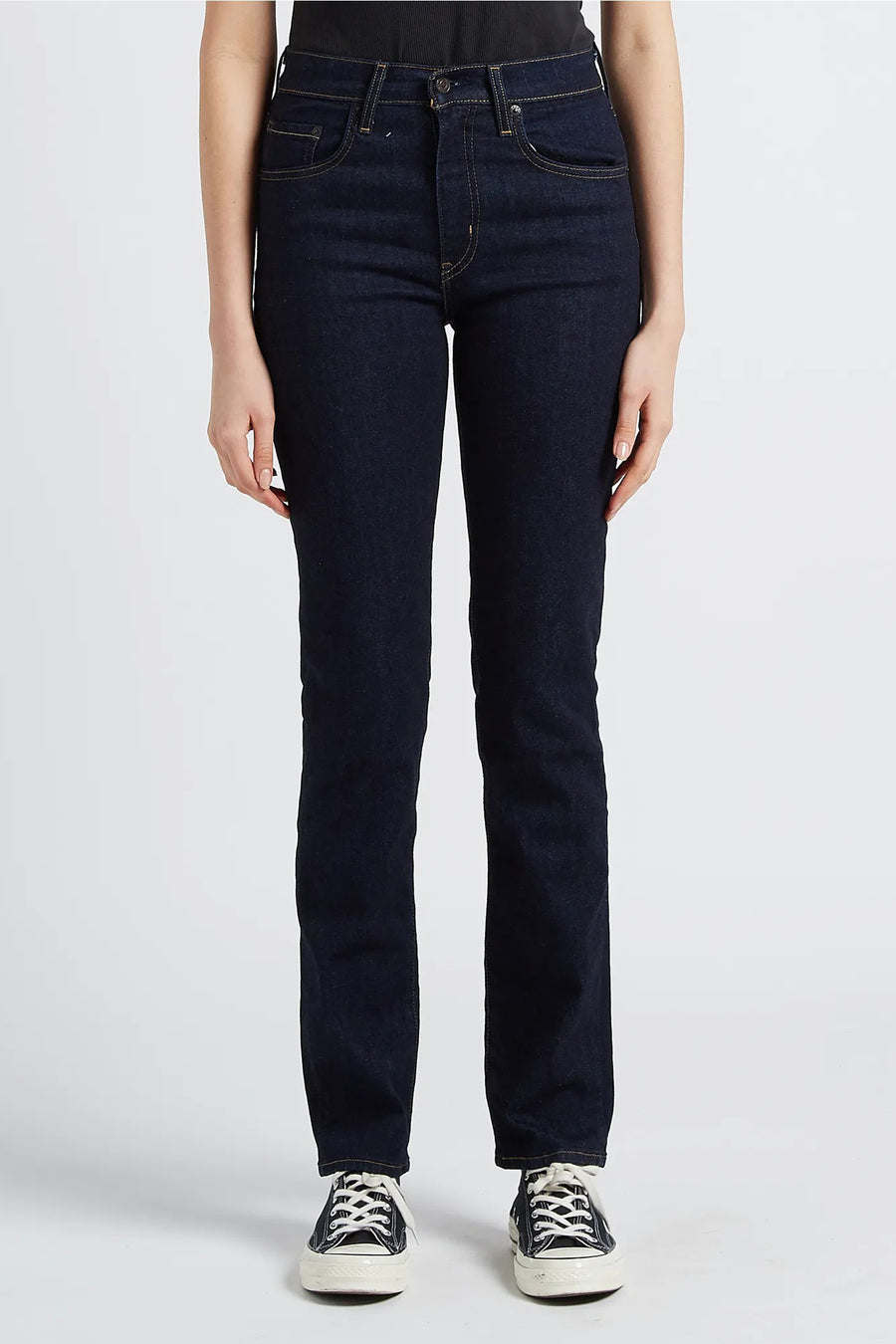 Rechte donkerblauwe spijkerbroek van Levi's, achterzakdetails en Converse schoenen.