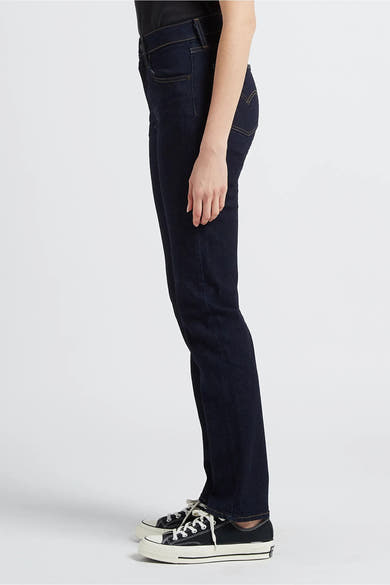 Rechte donkerblauwe spijkerbroek van Levi's®, gedragen met zwart-witte lage sneakers.