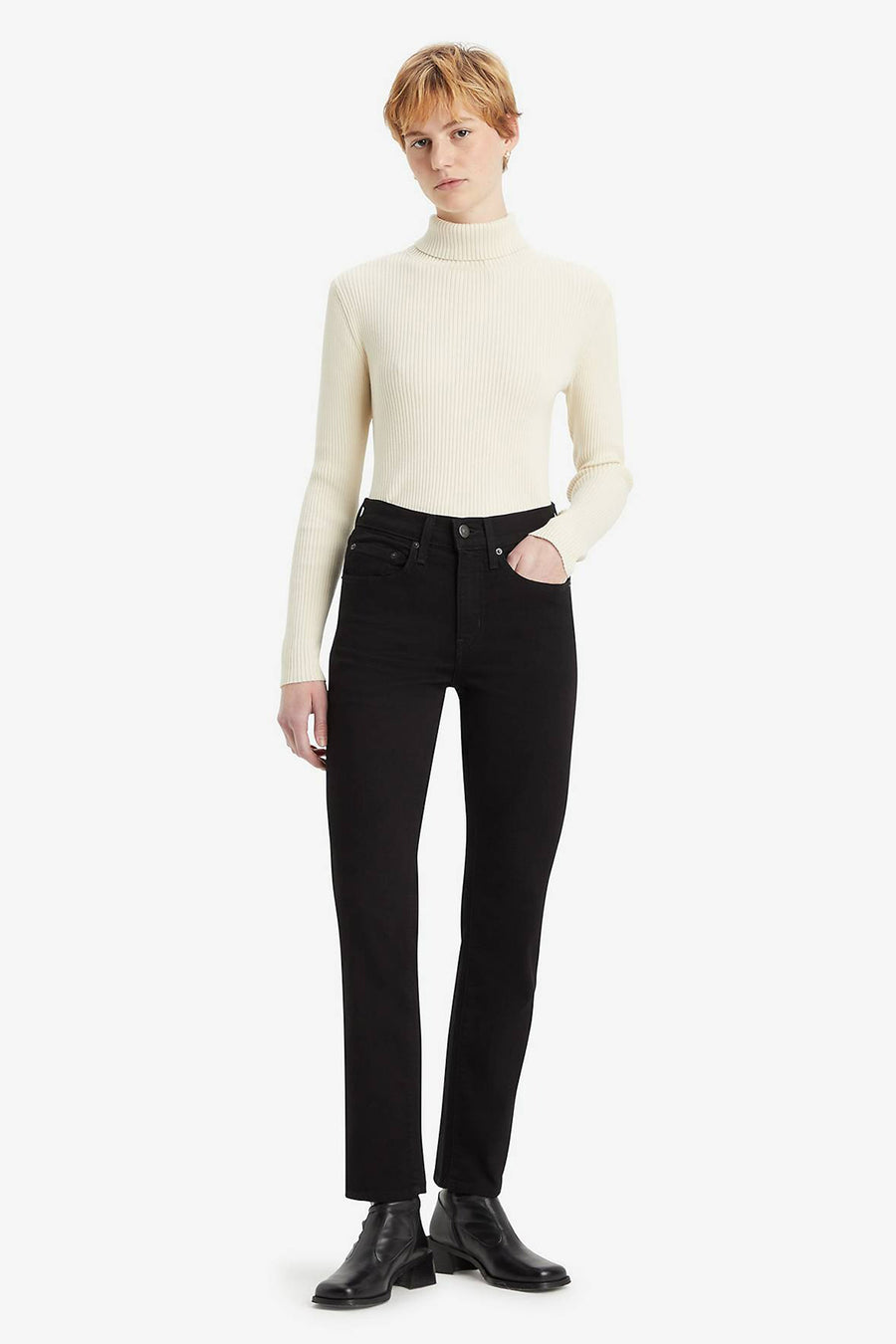 Jean droit en denim noir de Levi's®, porté avec un pull à col roulé ivoire et des bottines en cuir noir.
