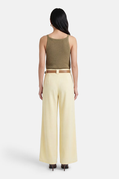 Gele Terra di Siena broek, met een bruine riem, wijde pijpen, gedragen met naaldhakken.