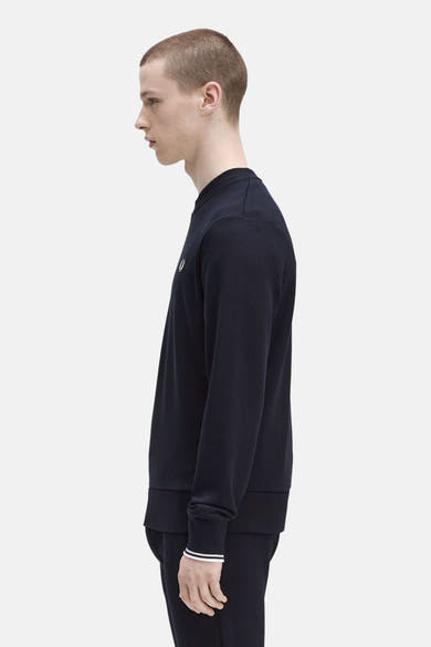 Marineblauwe sweater van FRED PERRY, lange mouwen, witte gestreepte manchetten, op een bijpassende joggingbroek, zijaanzicht.