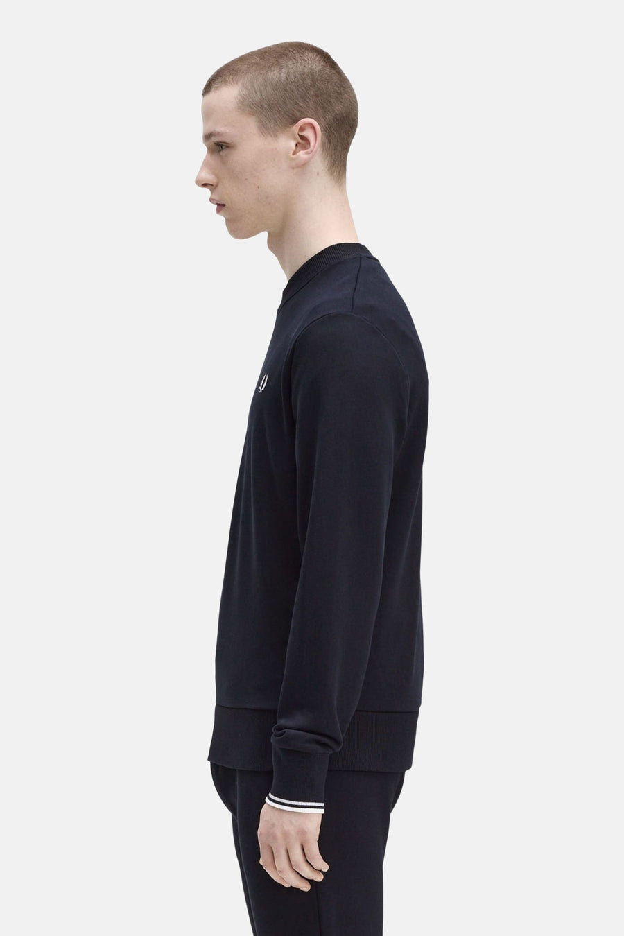 Marineblauwe sweater van FRED PERRY, lange mouwen, witte gestreepte manchetten, op een bijpassende joggingbroek, zijaanzicht.
