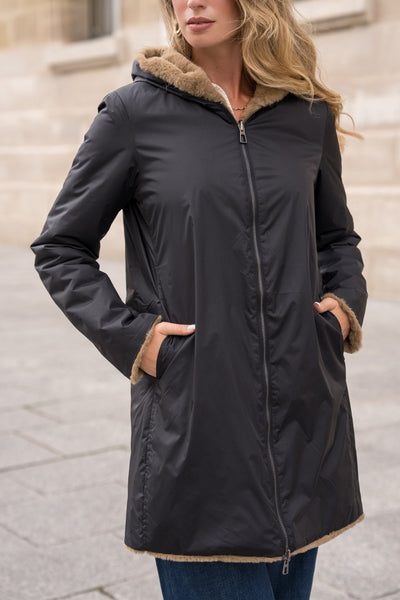 Imperméable noir de LAURA JO avec capuche doublée en fourrure beige, porté avec un jean.
