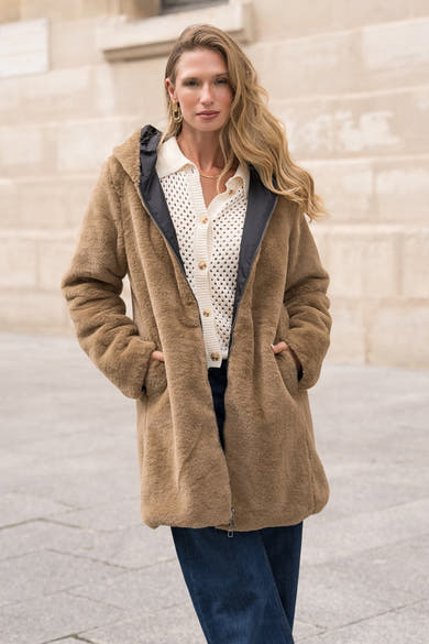 Zwarte regenjas van LAURA JO met een bruine teddyvoering en een witte cardigan.