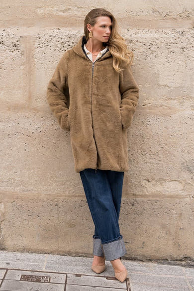 Zwarte regenjas van LAURA JO met ritssluiting, gedragen met opgerolde blauwe broek en nude schoenen.