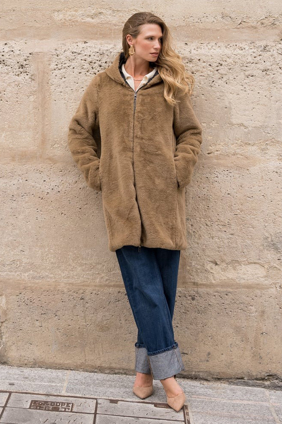 Zwarte regenjas van LAURA JO met ritssluiting, gedragen met opgerolde blauwe broek en nude schoenen.