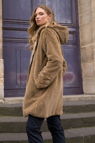 Beige regenjas van LAURA JO met capuchon, gedragen met een donkere broek, zijwaarts gezien.